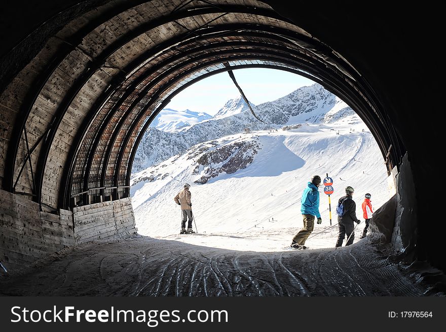 Skiers and snowboarders going out of tunnel connecting two sides of mountain. Skiers and snowboarders going out of tunnel connecting two sides of mountain.