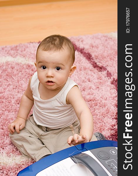 Cute caucasian baby with vacuum cleaner on the carpet