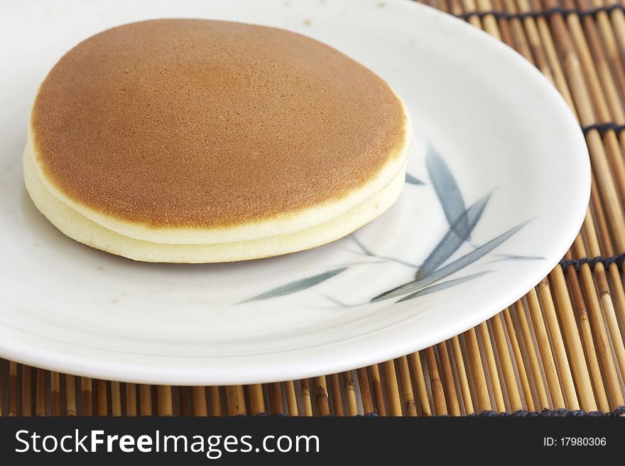 A pair of Japanese pancake stuffed with red bean or dorayaki on bamboo plate. A pair of Japanese pancake stuffed with red bean or dorayaki on bamboo plate