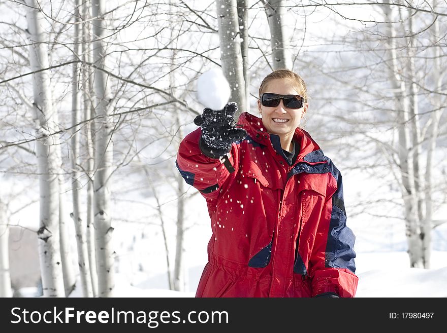 A woman hurls a snowball at the camera while playing in the snow on a winter day. A woman hurls a snowball at the camera while playing in the snow on a winter day