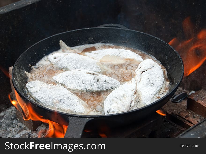 Golden fried fish in a skillet over an open fire