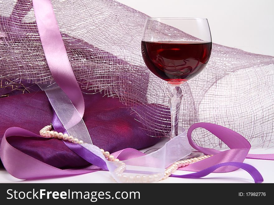 Glass with red wine on luxury background with beads and ribbons. Glass with red wine on luxury background with beads and ribbons