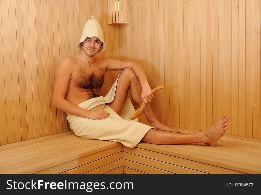 Young handsome man in a towel relaxing in a russian wooden sauna. Young handsome man in a towel relaxing in a russian wooden sauna