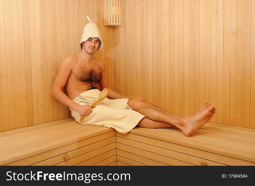 Young handsome man in a towel relaxing in a russian wooden sauna. Young handsome man in a towel relaxing in a russian wooden sauna