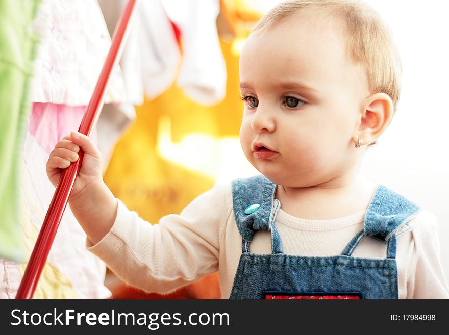 Beautiful little girl in a colored interior playing with a red metallic stick. Beautiful little girl in a colored interior playing with a red metallic stick