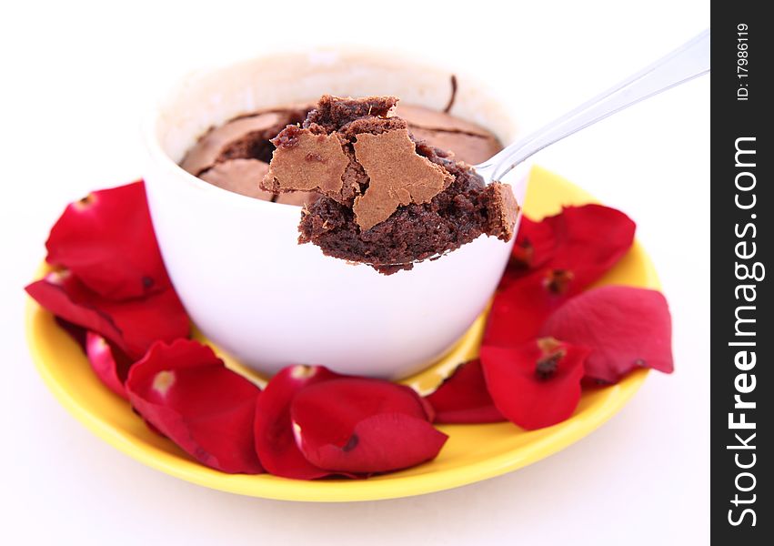 Chocolate souffle decorated with red rose petals being eaten with a spoon