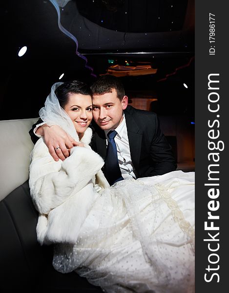 Elegant bride and groom in a wedding limousine
