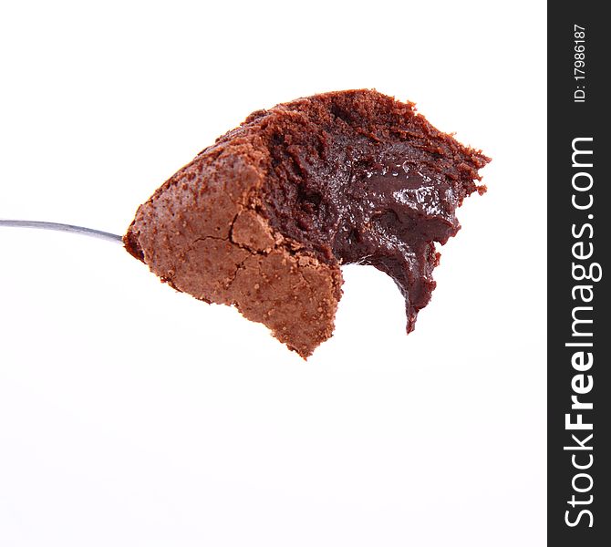 A bite of brownie on a spoon on a white background. A bite of brownie on a spoon on a white background