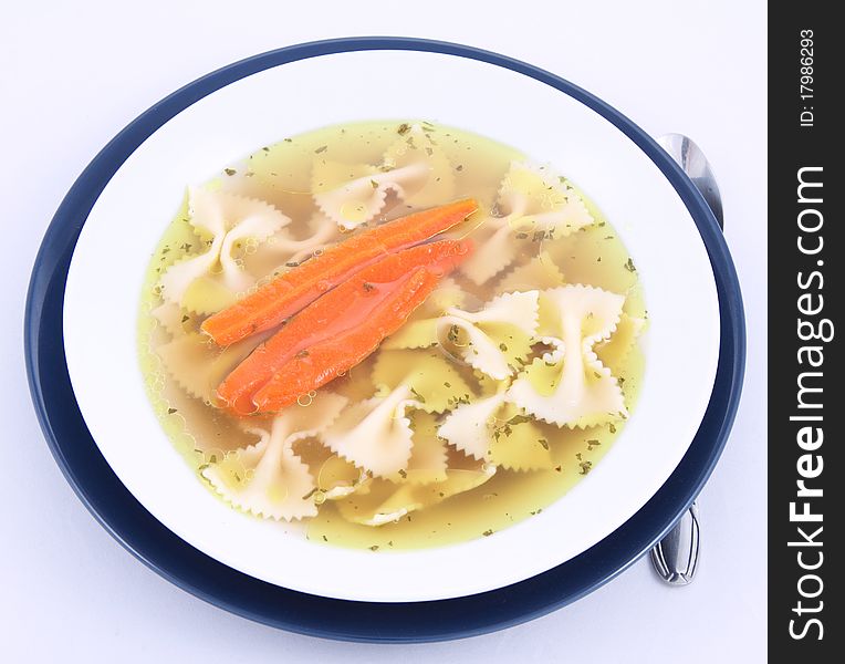 Chicken soup with farfalle pasta and carrots on a plate