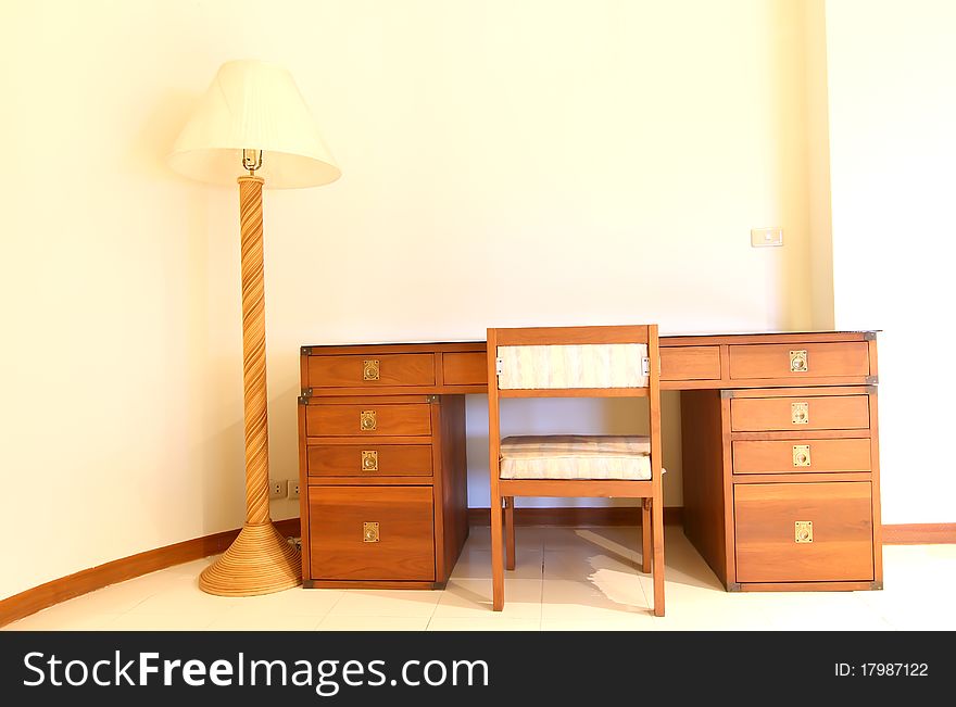 Detail of a wooden bedside table with three drawers and reading lamp