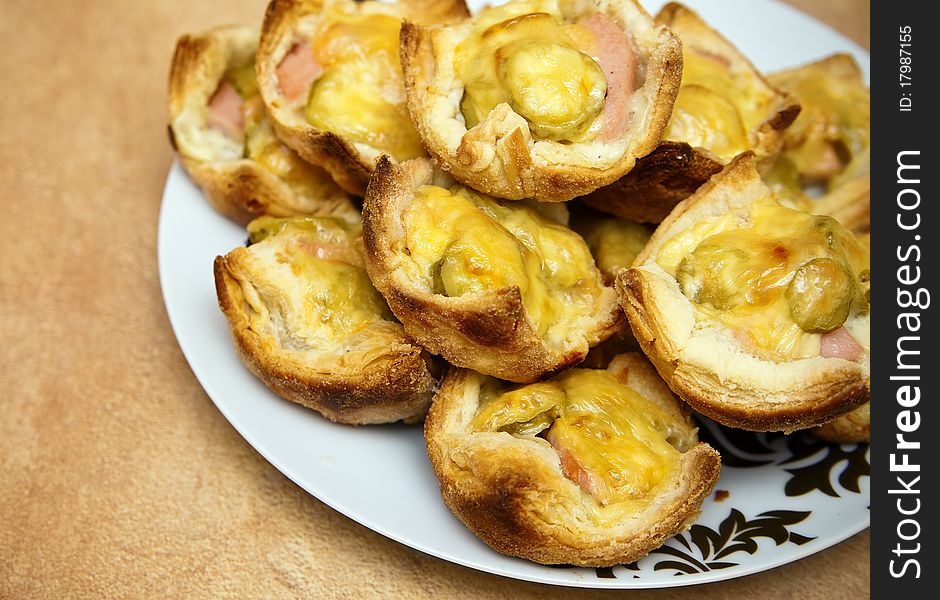 Close-up cakes made of puff pastry, sausages, pickles and cheese