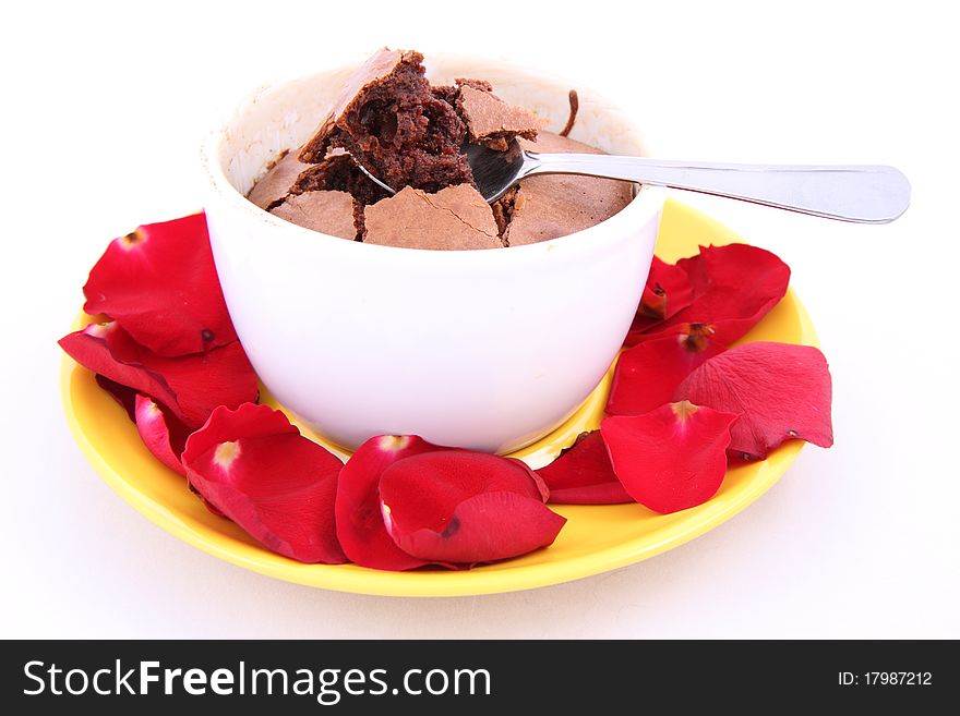 Chocolate souffle decorated with red rose petals being eaten with a spoon