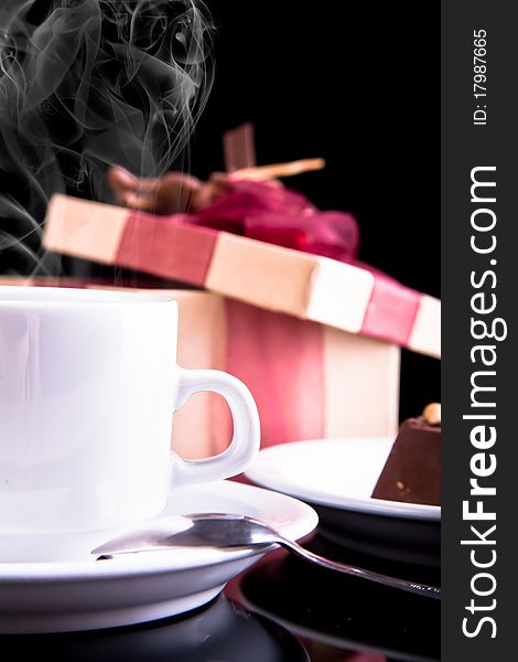 Tea, chocolate and gift on dark background