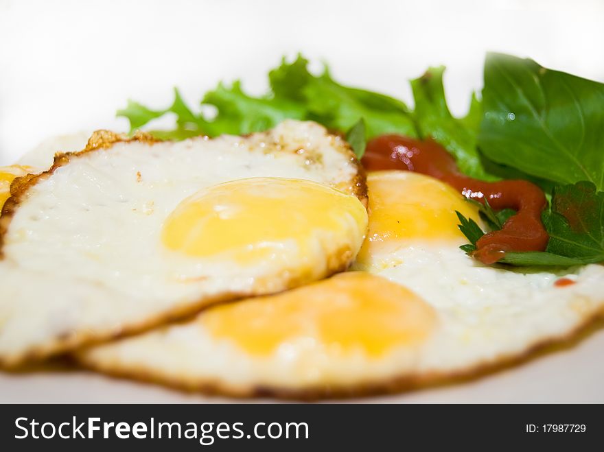 Fried tasty fried eggs with leaf salad on breakfast