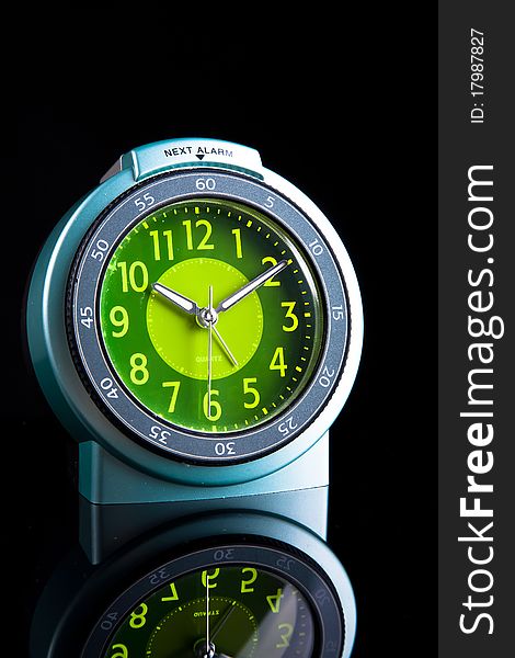 Green - blue alarm clock on dark background