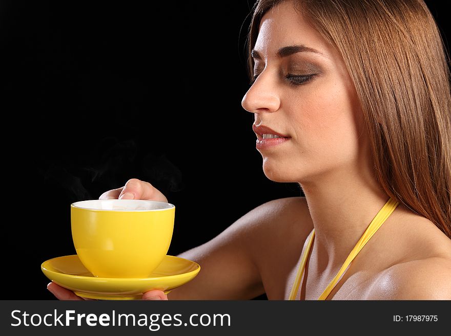 Headshot of beautiful young caucasion woman in holding yellow cup of tea up to her face, getting ready to drink. Headshot of beautiful young caucasion woman in holding yellow cup of tea up to her face, getting ready to drink.