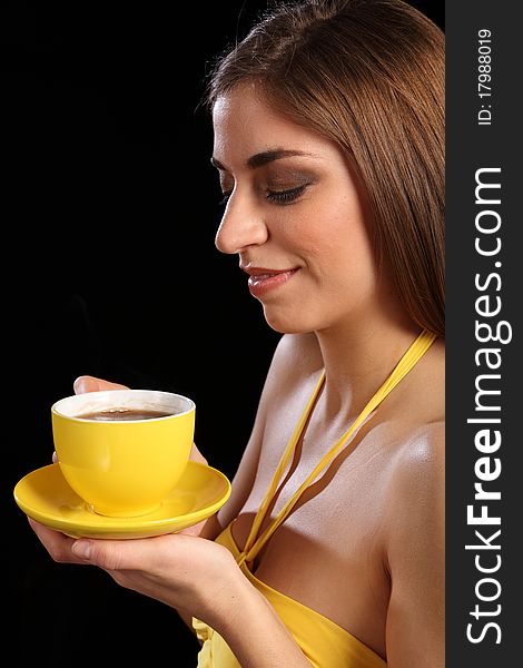 Portrait of a beautiful young caucasion woman drinking black tea from a yellow cup and saucer. Portrait of a beautiful young caucasion woman drinking black tea from a yellow cup and saucer.