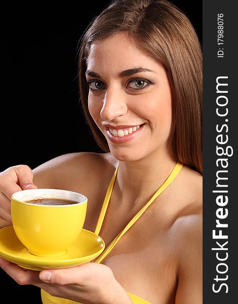 Portrait of a beautiful smiling young caucasion woman drinking black tea from a yellow cup and saucer. Portrait of a beautiful smiling young caucasion woman drinking black tea from a yellow cup and saucer.