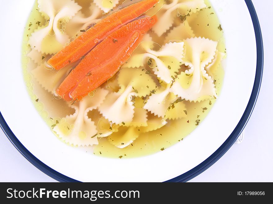 Chicken soup with farfalle pasta and carrots on a plate