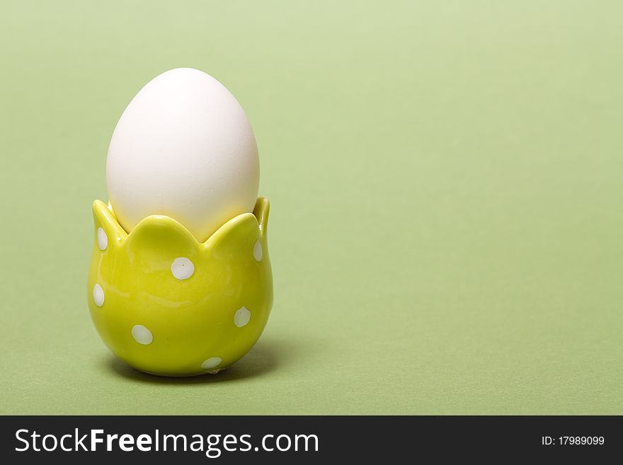 White easter eggs in yellow  eggcup on green background