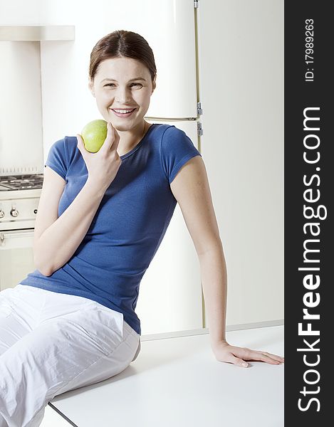 Woman eating an apple in the kitchen