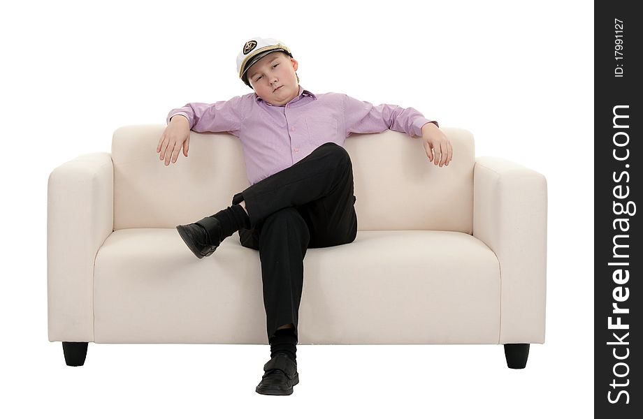 Serious young boy wearing a cap captain sitting on the couch