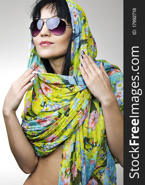 The beautiful girl in a motley scarf and sun glasses