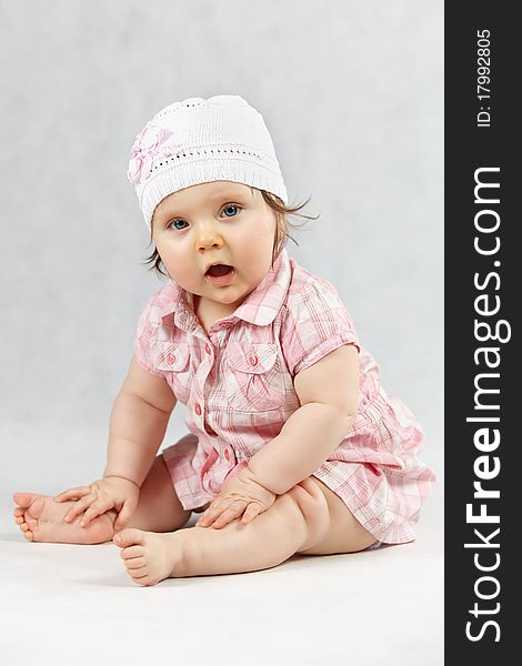 Sitting sweet baby in white cap - studio shot