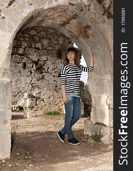 Young girl in jeans in an arch in the ruins