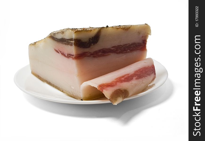 Piece of fat bacon with the cut off slice on a plate