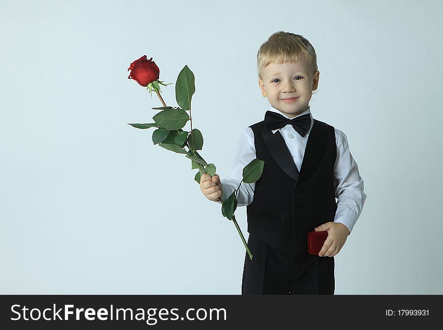 The little boy in a suit, with a rose in hands. The little boy in a suit, with a rose in hands