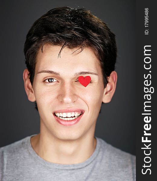 smiling man with small red heart on eye. smiling man with small red heart on eye