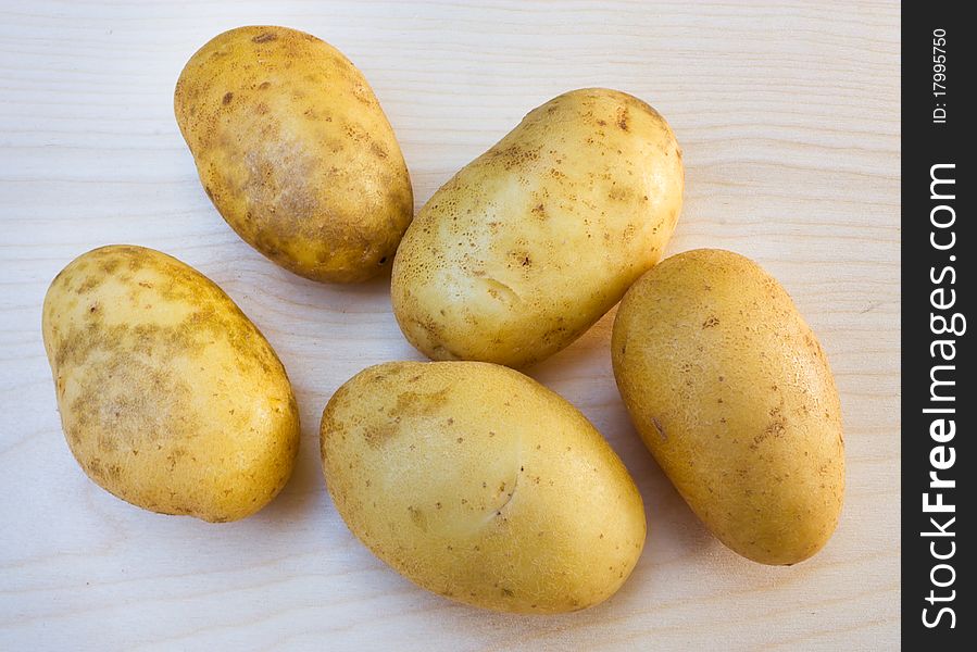 Yellow potato tubers on a wooden board. Yellow potato tubers on a wooden board