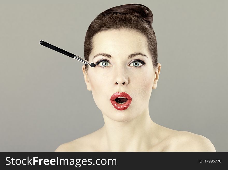 Portrait of beautiful woman with a brush for eyeshadow, doing makeup. Portrait of beautiful woman with a brush for eyeshadow, doing makeup