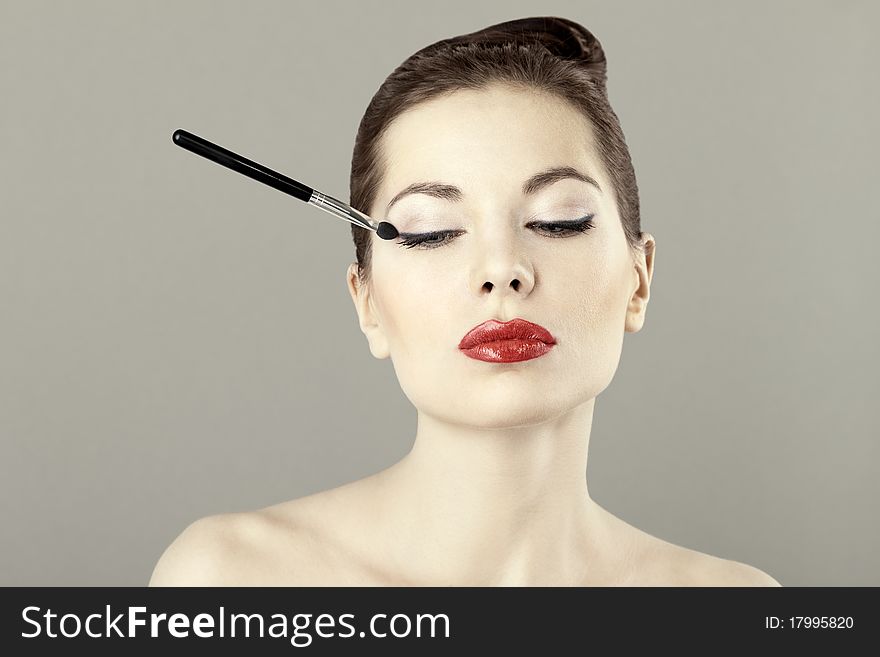 Portrait of beautiful woman with a brush for eyeshadow, doing makeup. Portrait of beautiful woman with a brush for eyeshadow, doing makeup