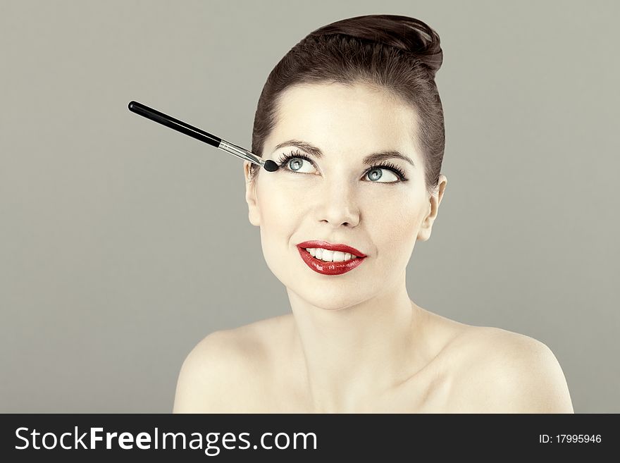 Portrait of beautiful woman with a brush for eyeshadow, doing makeup. Portrait of beautiful woman with a brush for eyeshadow, doing makeup