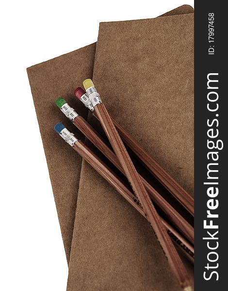 Automatic colored pencils on top of a plain brown notebook-isolated. Automatic colored pencils on top of a plain brown notebook-isolated.
