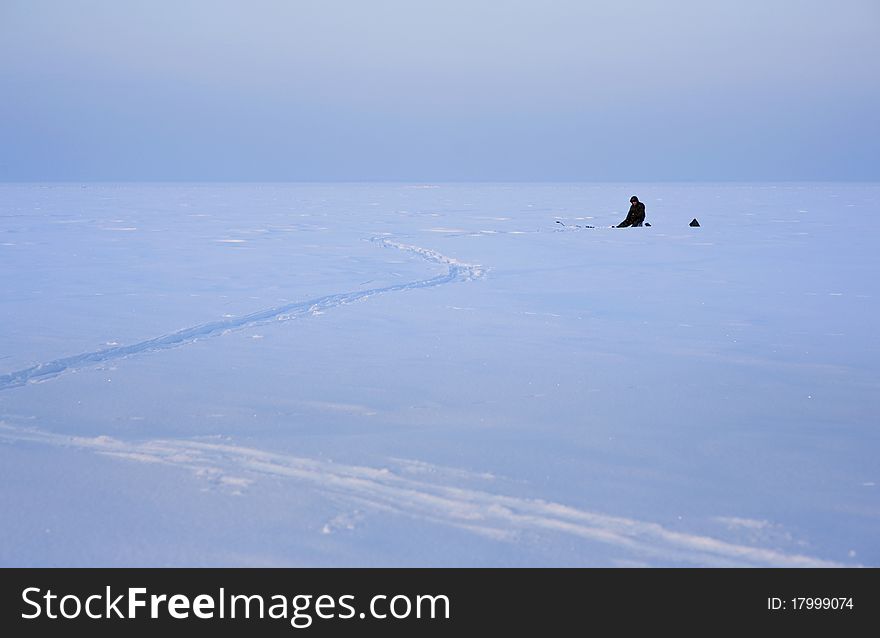 Lonely fisherman on the snow winter lake