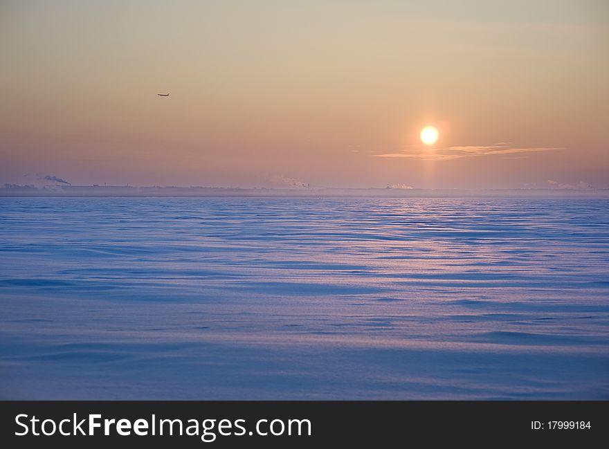 Sunset in winter with deep snow and airplane on horizon