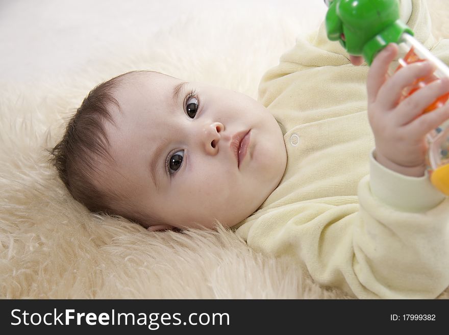 Lovely brown-eyed baby lies on white fur. Lovely brown-eyed baby lies on white fur