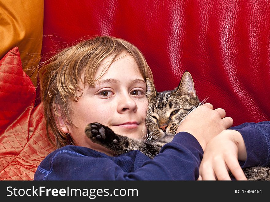 Young boy is hugging his cat at the sofa