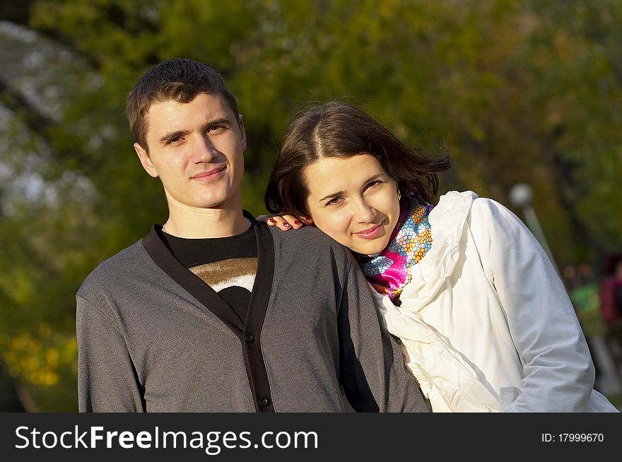 Young couple portrait over defocused autumn park background. Young couple portrait over defocused autumn park background