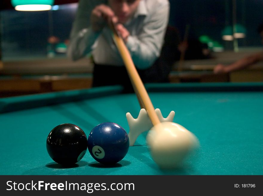 Man shooting pool with white, blue and black balls on table