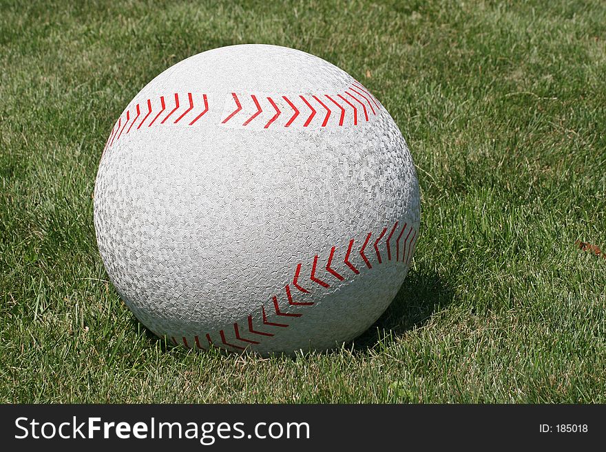 A huge baseball on green grass. A huge baseball on green grass.