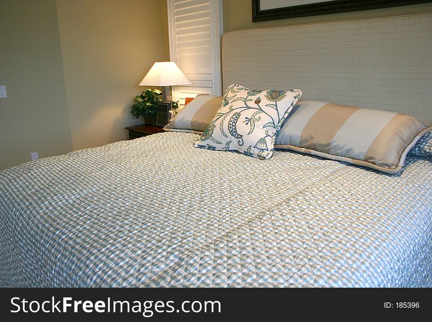 Beautiful blue bedroom, with silk pillows and quilted bedspread and headboard