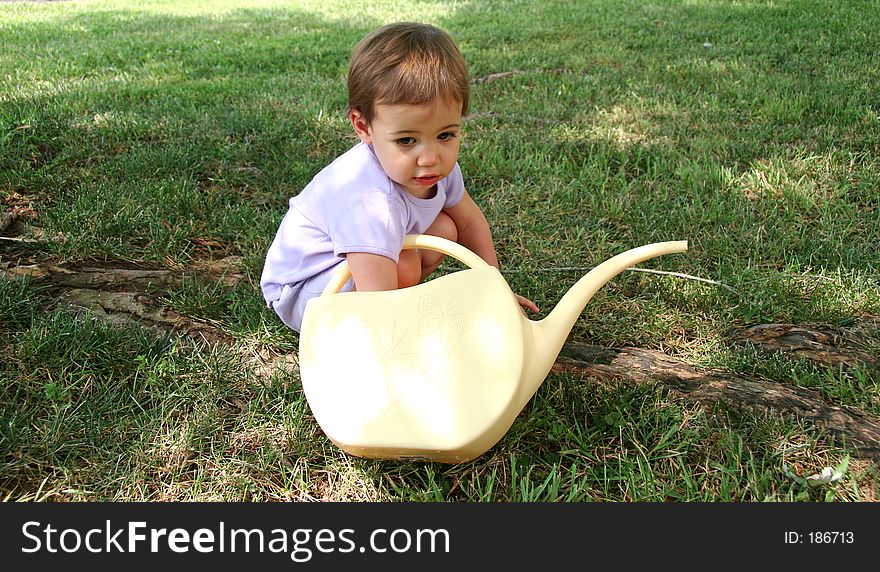 Picture of a baby girl with her hand in a watering can. Shot with a Canon 20D. Picture of a baby girl with her hand in a watering can. Shot with a Canon 20D.