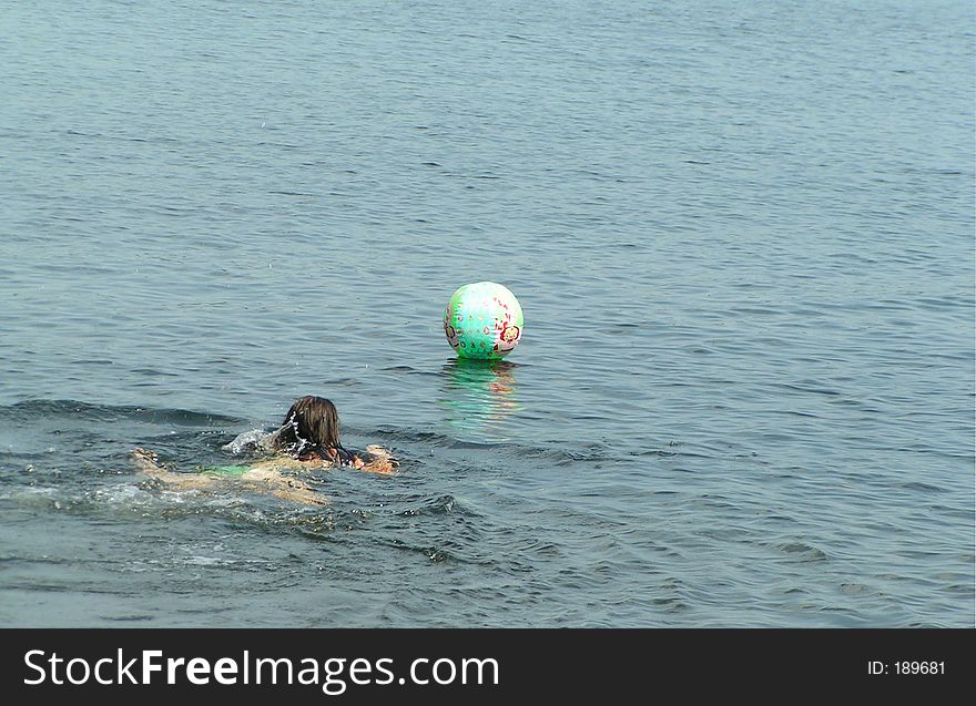 Girl rescueing her beach ball in the lake. Girl rescueing her beach ball in the lake.