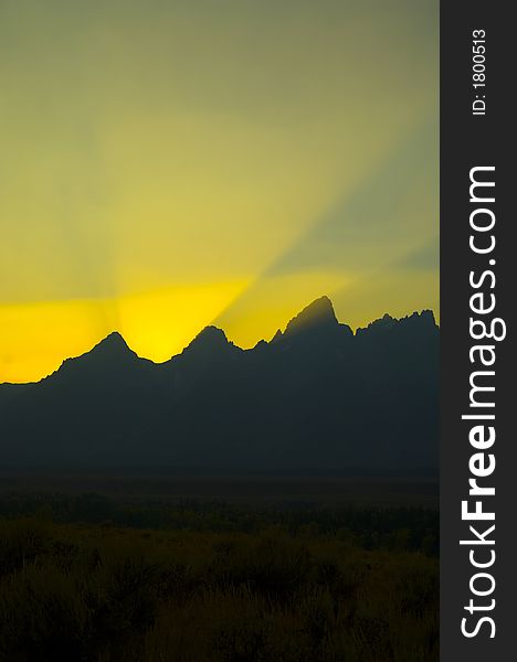 Sunbeams brighten the sky at sunset over the silhouetted mountains in Grand Teton National Park. Sunbeams brighten the sky at sunset over the silhouetted mountains in Grand Teton National Park