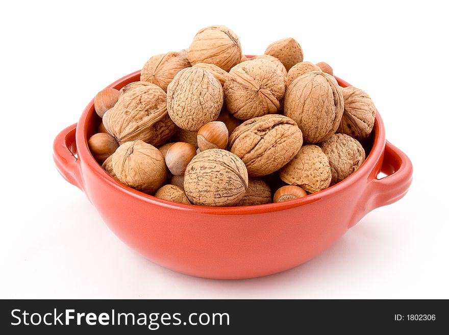 Red bowl with mixed nuts, walnuts, hazelnuts, almonds. White background, isolated.