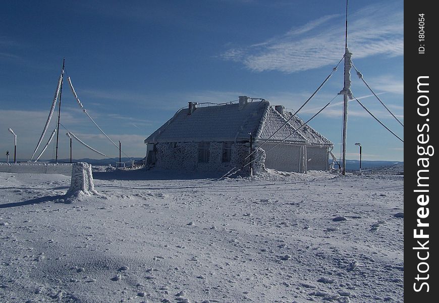 A house on the top of the mountain covered and surrounded by snow. A house on the top of the mountain covered and surrounded by snow